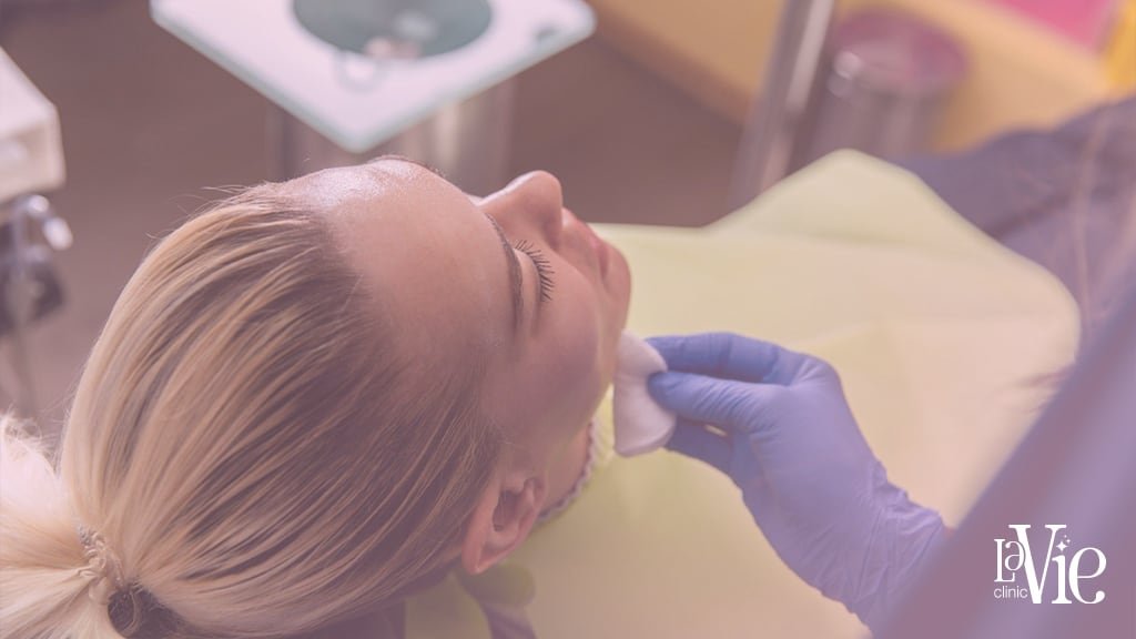 a person lying down with a Doctor padding on her face with a cotton befor the PRF facial injection, LaVie Rochester hills